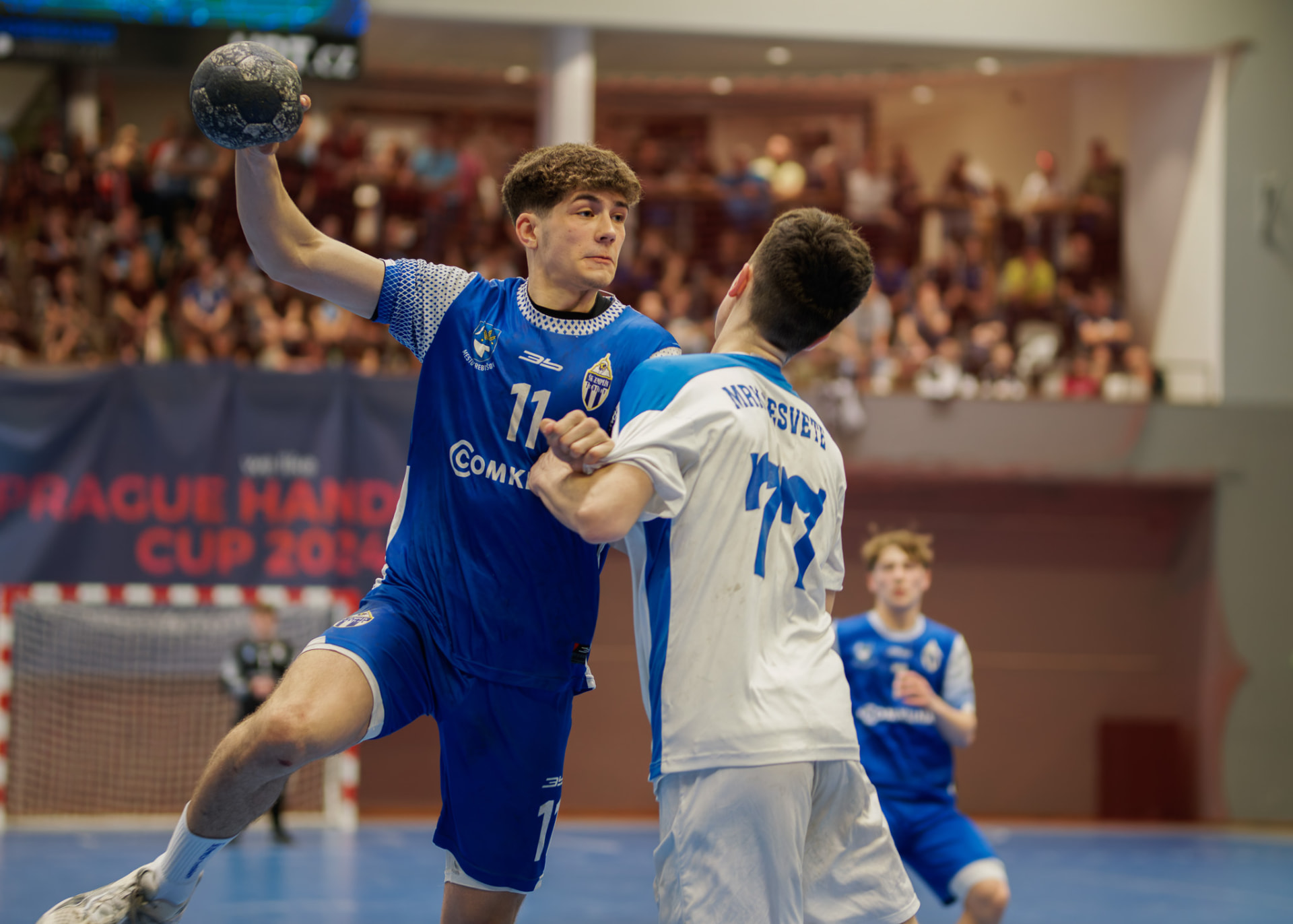 Tireur en maillot bleu face à un défenseur lors d'un match de la Prague Handball Cup